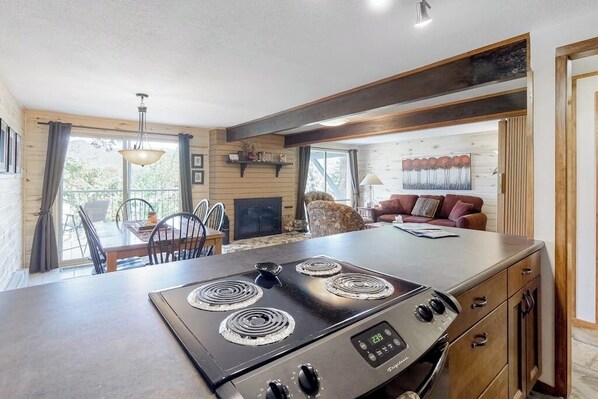 A kitchen with a stove, dining table, chairs, and a sofa in a cabin-style interior. - Beautiful mountain home steps to ski slopes with fireplace (Durango)