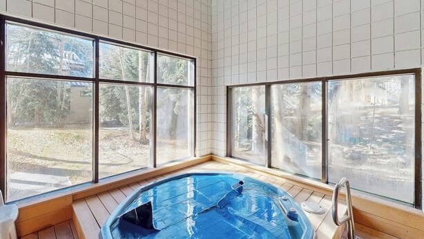 Ett rum med ett stort fönster, ett trägolv och en blå pool.