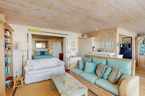 A cozy room with a bed, a sofa, a small table, and a bookshelf.