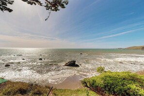 A coastal landscape with rocky terrain, a body of water, and a clear sky.