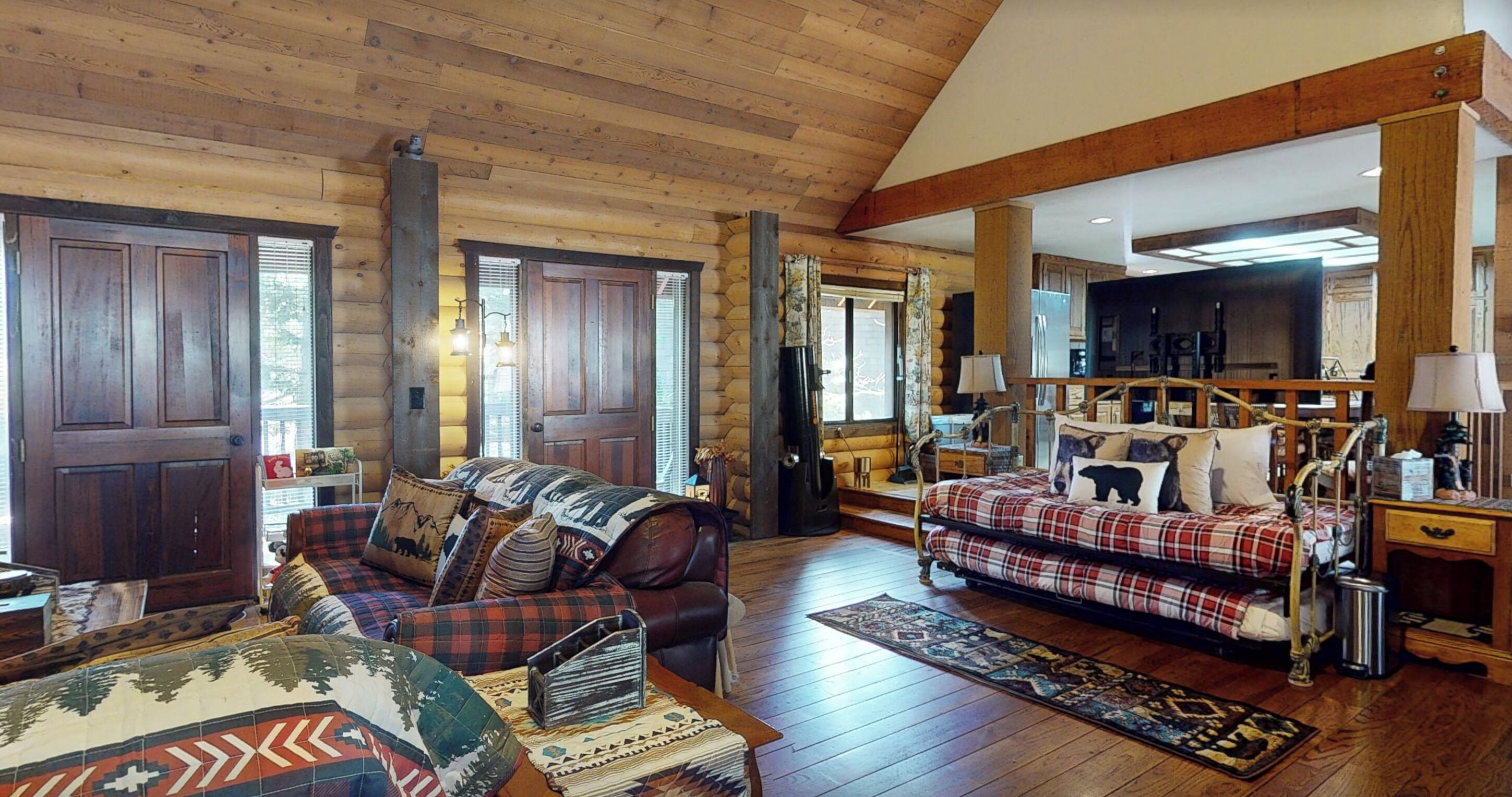 Een vakantiehuisje van binnen met een groot bed, een bank en een open haard.