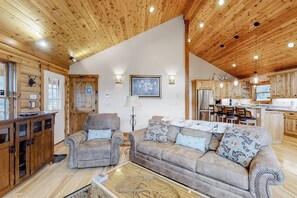 Ein Holzblockhaus-Interieur mit Wohnzimmer, Küche und Essbereich.