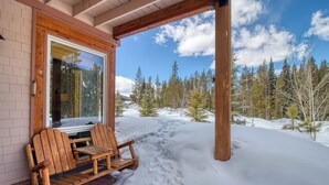 A wooden bench outside a building with a snowy landscape and trees in the background.