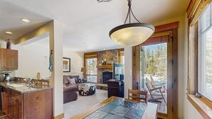 A spacious living area with a fireplace, a dining table, and a view of the outdoors.