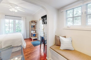 Ein Schlafzimmer mit Bett, Schreibtisch, Stuhl, Bücherregal und Fenster.