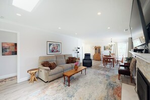 Ein Wohnzimmer mit einer Couch, einem Couchtisch und einem Essbereich mit Stühlen und Tisch.