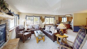 Ein gemütliches Wohnzimmer mit Ledersofas, einem Kamin und einer Küche im Hintergrund.