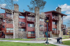A multi-story building with balconies, stone facade, and a clear sky. - Cozy mountain condo with ski-in access, hot tub & stunning views (Breckenridge)