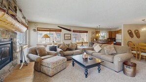 Ein Wohnzimmer mit Kamin, zwei Sofas, einem Couchtisch und einer Küche im Hintergrund.