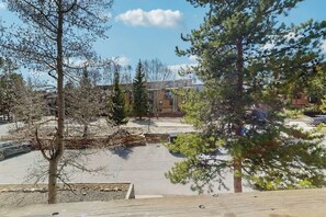 A parking lot with trees, a building with multiple windows, and a clear sky. - Cozy mountain condo with ski-in access, hot tub & stunning views (Breckenridge)