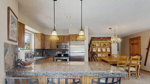 Eine Küche mit Granit-Arbeitsplatten, Edelstahlgeräten, Holzausbau und einem Essbereich mit Holztisch und -stühlen.