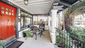 A covered outdoor area with a red door, wicker furniture, and potted plants. - Old Yacht Club Inn All-Suite Getaway - 1 Block to East Beach, Walk Everywhere (Santa Barbara)
