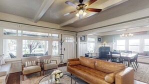 A spacious living room with a leather sofa, a round coffee table, and a ceiling fan. - Old Yacht Club Inn All-Suite Getaway - 1 Block to East Beach, Walk Everywhere (Santa Barbara)