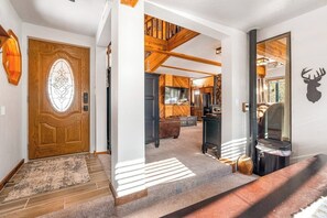 Eine Holztür mit einem Buntglasfenster, eine Treppe, die zu einem Erker führt, und ein Damhirsch-Wandbild.