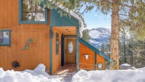 En stuga av trä med en ytterdörr, en brevlåda och ett snötäckt landskap.