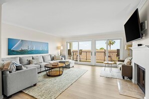 A living room with a sofa set, a coffee table, a fireplace, and a TV mounted on the wall. - Ocean-view condo in Santa Barbara steps to beach with pool & balcony (Santa Barbara)