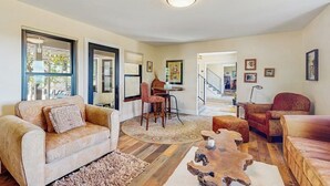 Una sala de estar amplia con sofá, sillón, mesa de centro y comedor con sillas.
