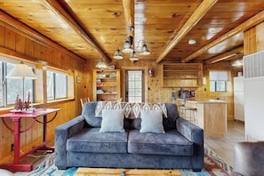 A cozy cabin interior with a sofa, a table, and a kitchen area.