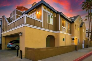 Ein zweistöckiges Haus mit Garage, Balkon und gut beleuchteter Fassade.