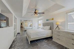 Ein Schlafzimmer mit einem Bett, einem Schminktisch, einem Deckenventilator und Blick auf den Flur.