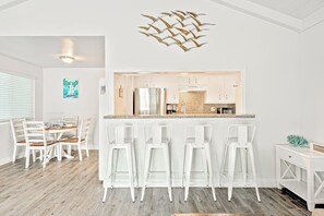 Eine moderne Küche mit weißen Schränken, einer zentralen Kochinsel und Barhocker.
