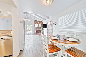 Eine moderne Küche mit Spülmaschine, ein Essbereich mit Holztisch und Stühlen sowie ein Kamin aus Ziegeln.