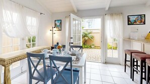 Uma sala de jantar com uma mesa branca, cadeiras azuis e vista para o exterior.