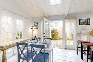 A dining area with a white table, blue chairs, and a view of the outside.
