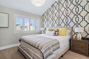 A bedroom with a bed, bedside tables, a patterned wall, and a window. - Newly renovated condo, closest walk to theme parks - pools & hot tub on-site (Anaheim)