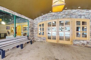 A stone-walled room with a bench, a wooden cabinet with glass doors, and a hanging light fixture. - Bright and colorful studio with breathtaking mountain views (Keystone)