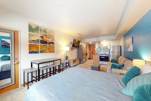 A modern hotel room with a large bed, a desk, a kitchenette, and a bathroom. - Bright and colorful studio with breathtaking mountain views (Keystone)
