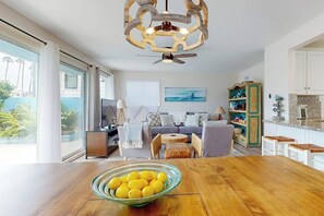 Ein modernes Wohnzimmer mit einem Holzesstisch, einer Sofagarnitur und einer Küchenzeile mit einem grünen Schrank.