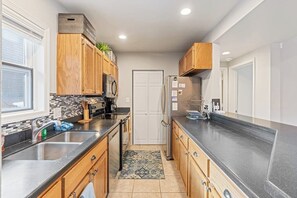 Eine moderne Küche mit Holzausstattung, einer Spüle aus Edelstahl und einem Kühlschrank.