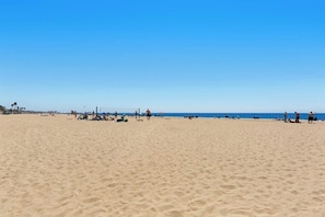 Ein weiter Sandstrand mit Menschen und Sonnenschirmen.
