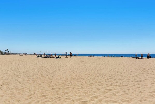 A wide sandy beach with people and umbrellas. - Spacious condo steps from the beach with full kitchen - dog-friendly (Newport Beach)