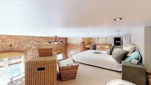A cozy bedroom with a brick wall, a bed, a sofa, and wicker baskets. - Stylish, downtown condo w/ loft, kitchen, & fireplace plus shared patio & grill (Durango)