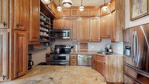 A kitchen with wooden cabinets, stainless steel appliances, and pendant lighting. - Stylish, downtown condo w/ loft, kitchen, & fireplace plus shared patio & grill (Durango)