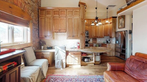 A kitchen with wooden cabinets, a central island, and a red leather couch. - Stylish, downtown condo w/ loft, kitchen, & fireplace plus shared patio & grill (Durango)