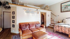 A bedroom with a loft bed, a leather sofa, a patterned rug, and a staircase. - Stylish, downtown condo w/ loft, kitchen, & fireplace plus shared patio & grill (Durango)