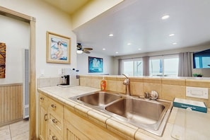 A modern kitchen with a double sink, wooden cabinets, and a coffee maker. - Waterfront home with beautiful ocean views & beach access (Newport Beach)