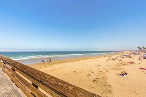 Ein Strand mit Holzsteg, Sand und Blick auf das Meer.