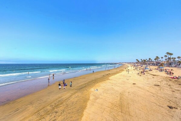 A beach with a wide sandy area, a clear blue sky, and the ocean. - Waterfront home with beautiful ocean views & beach access (Newport Beach)