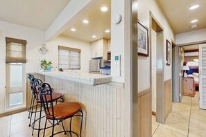 A kitchen with a bar area, wooden chairs, and a refrigerator. - Waterfront home with beautiful ocean views & beach access (Newport Beach)