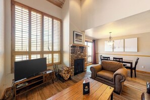Ein Wohnzimmer mit Kamin, Fernseher, einer Couch und einem Essbereich.