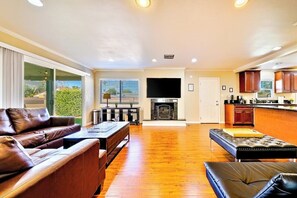 Ein geräumiges Wohnzimmer mit Kamin, Ledersofas und einem Fernseher.