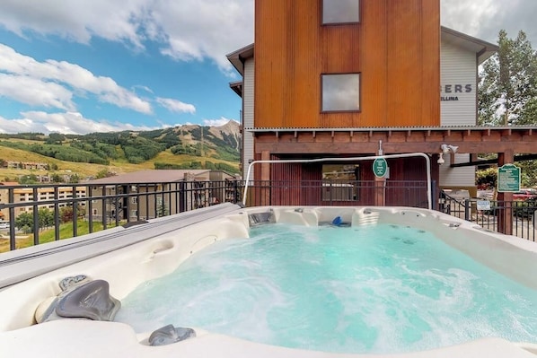 Ein Whirlpool mit Blick auf die Berge, ein Holzgebäude und ein Schild mit Text.