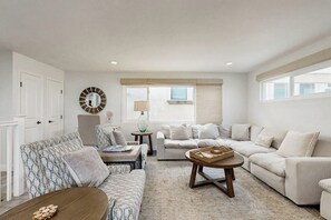 Ein Wohnzimmer mit einem gemusterten Sofa, einem runden Couchtisch und einem beigefarbenen Sitzsofa.