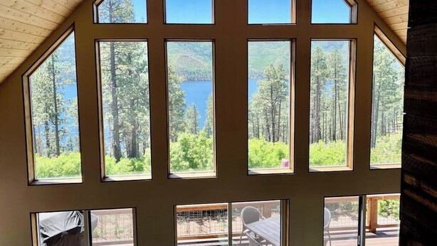 Una habitación con amplios ventanales que dan a un lago y un bosque.