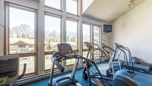 A gym with treadmills, a stationary bike, and a rowing machine, large windows with a mountain view, and a TV mounted on the wall. - Spacious Family Getaway W/ Private Balcony, Skiing Nearby & High-Speed WiFi (Durango)