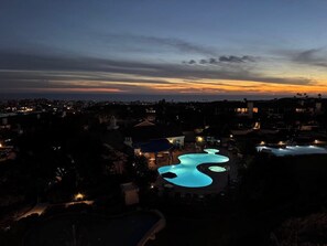 A resort with a pool area, surrounded by buildings and a sunset sky. - Ocean-view condo, balcony, clubhouse, gym, pool, hot tub, snowbird haven (Newport Beach)